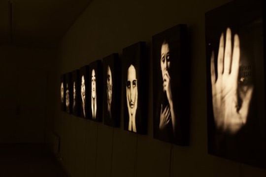The opposing wall: ten lit lightboxes of SOLIENNE-generated portraits receding down the corridor.